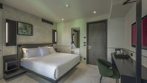 A modern hotel room with a large bed, bedside tables, a desk with a chair, a mirror, and a door. - Palazzo Vittoria Hotel Milano (Milan)