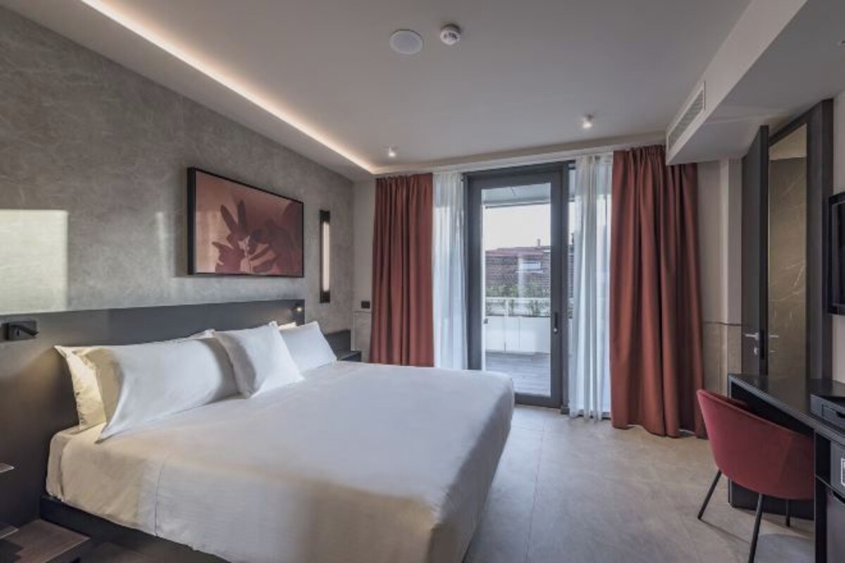 Habitación de hotel moderna con una cama grande, un escritorio y vistas al exterior.