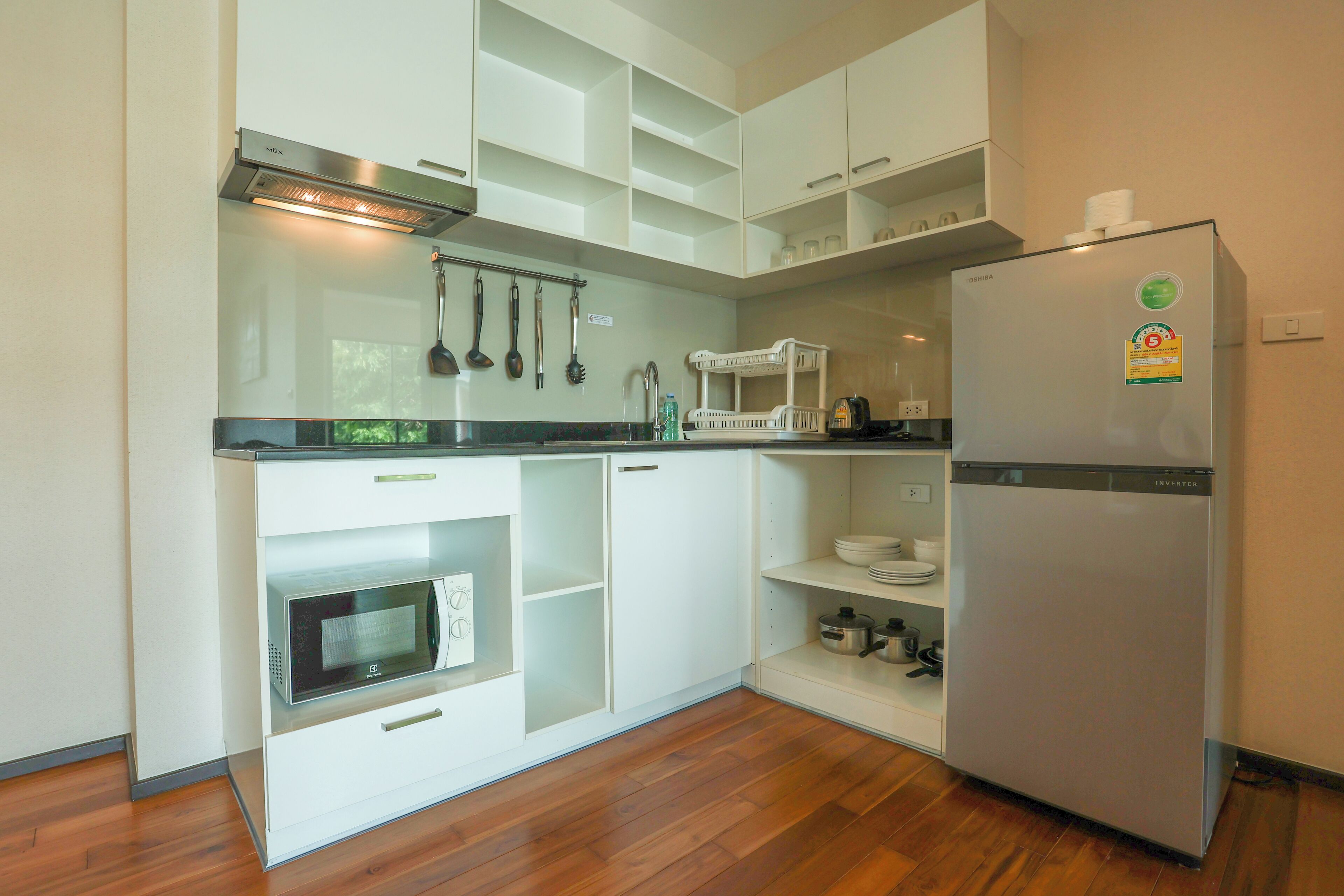 A modern kitchen with white cabinets, a built-in microwave, and a stainless steel refrigerator.