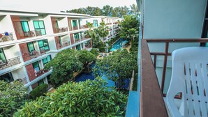 Ein mehrstöckiges Hotel mit Balkonen, einem Schwimmbad und üppiger Bepflanzung.