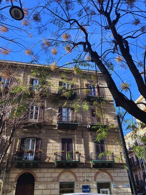 Un immeuble à plusieurs étages, doté de balcons, avec une devanture visible et un ciel d’un bleu éclatant.