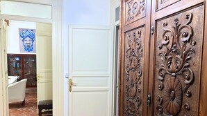 Una habitación con una puerta blanca, un mueble de madera con tallas elaboradas, suelo de mármol y un adorno azul en la pared.