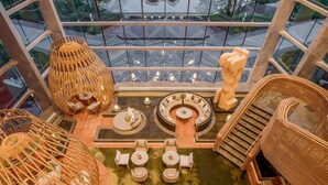 Ein Atrium mit hohen Decken und einer zentralen Sitzgruppe, umgeben von Korbmöbeln und einer Treppe.