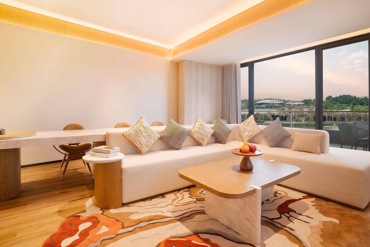 A modern living room with a sofa, a coffee table, and a dining area with a marble countertop.