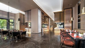 Un amplio comedor de hotel con una larga barra, varias mesas y sillas.