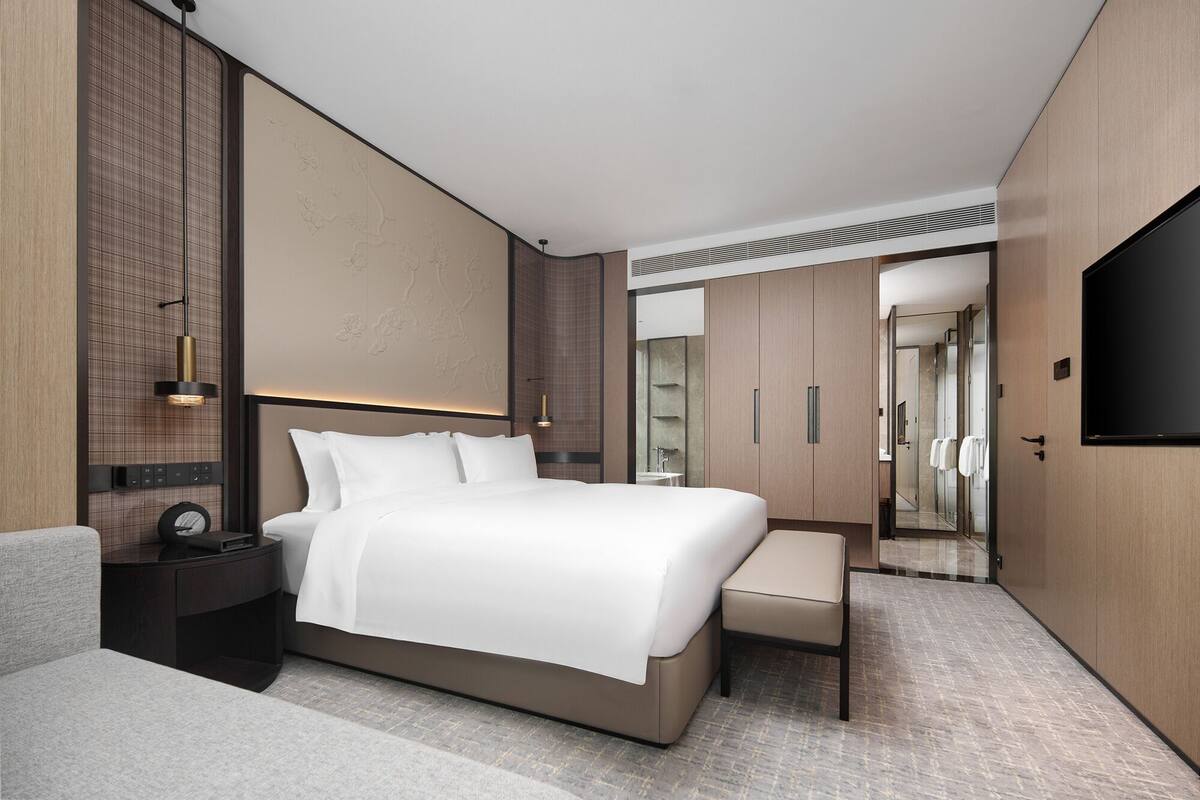Une chambre d’hôtel moderne dotée d’un grand lit, de tables de chevet, d’un coin salon et d’une télévision.