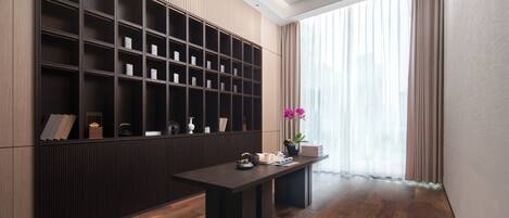 Una habitación moderna con piso de madera oscura, una amplia estantería y una mesa con un florero y una planta en maceta.