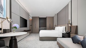 Una habitación de hotel moderna con una cama grande, un escritorio y una zona de estar.