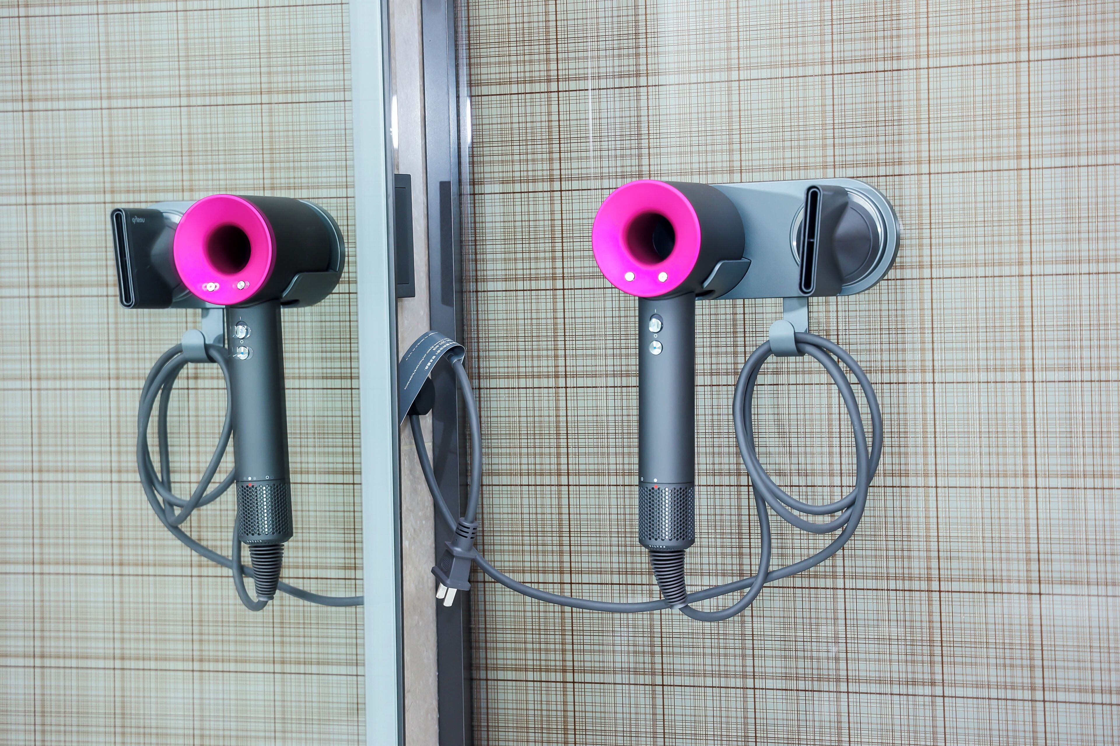 Two hair dryers mounted on a wall with a grid-patterned background.