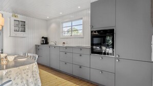 Eine moderne Küche mit weißen Schränken, einem eingebauten Backofen und einem Fenster für natürliches Licht.