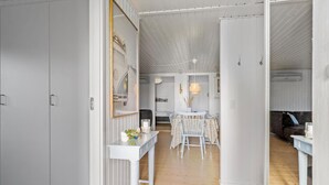 Ein Flur, der in einen Essbereich mit einem weißen Tisch und Stühlen, einem Spiegel und einem gerahmten Bild an der Wand führt.