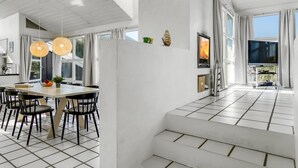 A modern kitchen with a dining area, a fireplace, and a TV.
