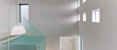 A modern interior with a staircase, a hanging light fixture, and a visible fire extinguisher.