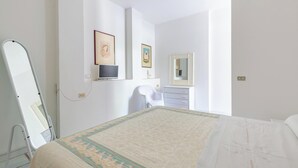 Une chambre à coucher avec un lit, une chaise, un bureau et un miroir.