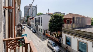 A street view with buildings, a parked car, and a pedestrian. - Charming Studio w/ Balcony, A/C and Kitchen (Porto)