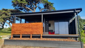 A modern, single-story cabin with a wooden deck and a sliding door leading to a room. - Hole in the rock studio
Welcome to the hole in the rock Studio,  (Cape Foulwind)