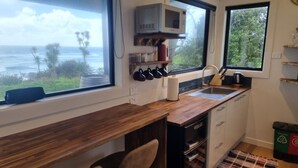 A compact kitchen with a wooden countertop, a built-in microwave, and a view of the ocean. - Hole in the rock studio
Welcome to the hole in the rock Studio,  (Cape Foulwind)