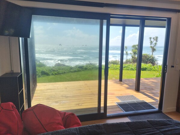 A room with a large sliding glass door leading to a wooden deck overlooking the ocean. - Hole in the rock studio
Welcome to the hole in the rock Studio, (Cape Foulwind)
