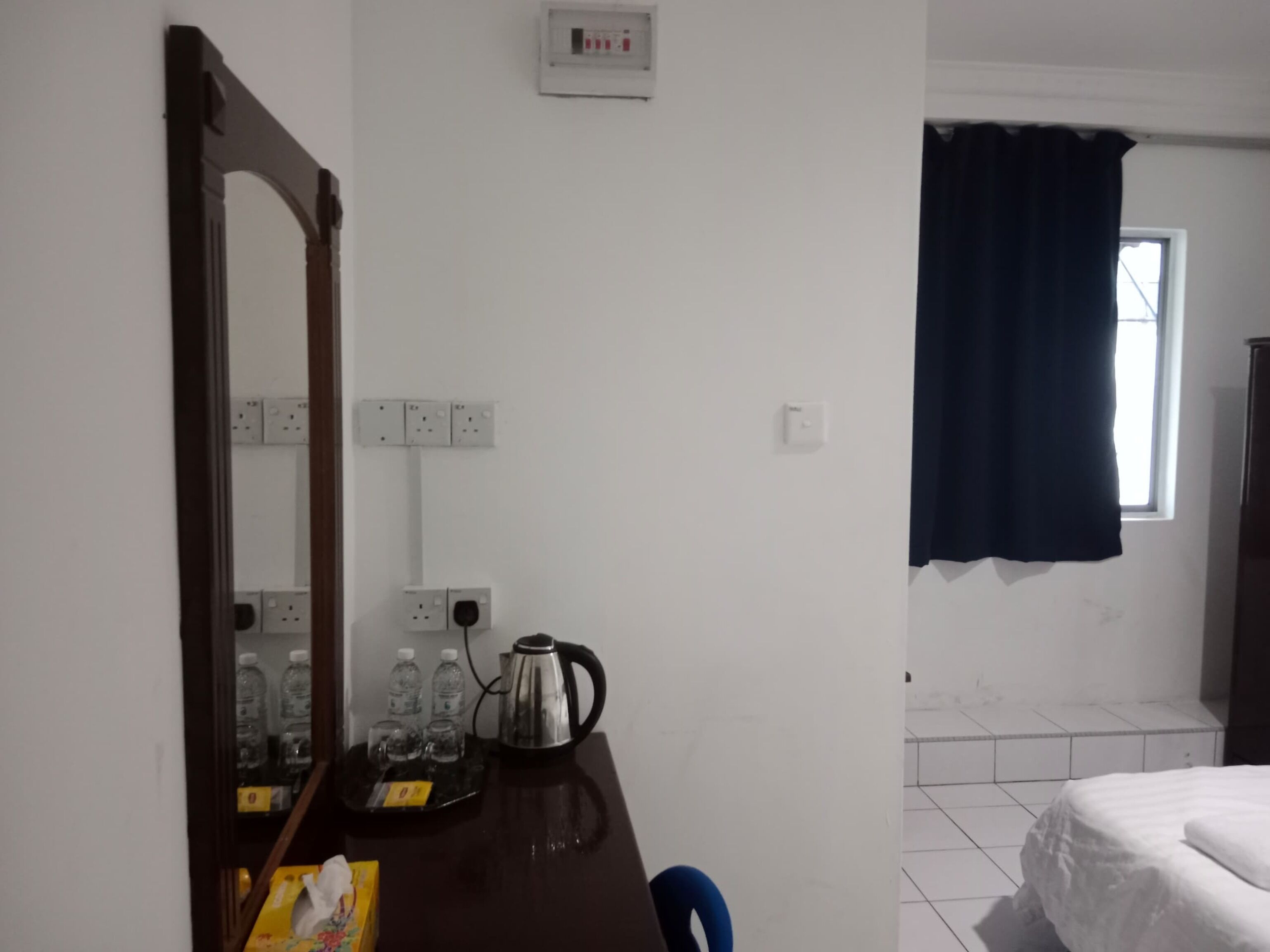 Ett hotellrum med ett skrivbord i trä, en spegel, en vattenkokare och en säng.