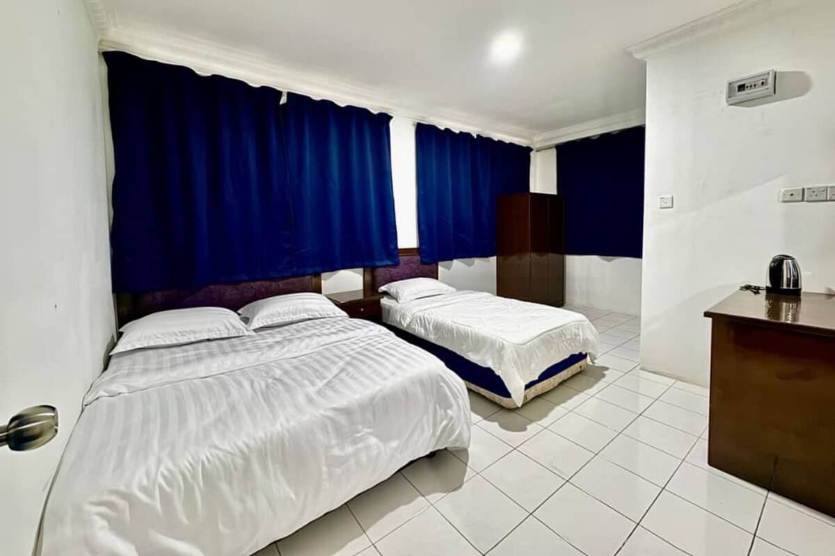 Habitación de hotel con dos camas, un escritorio y un armario.