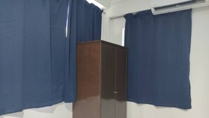 A room with a wardrobe, blue curtains, and an air conditioning unit. - Hotel O Vaigan Hotel (Bintulu)