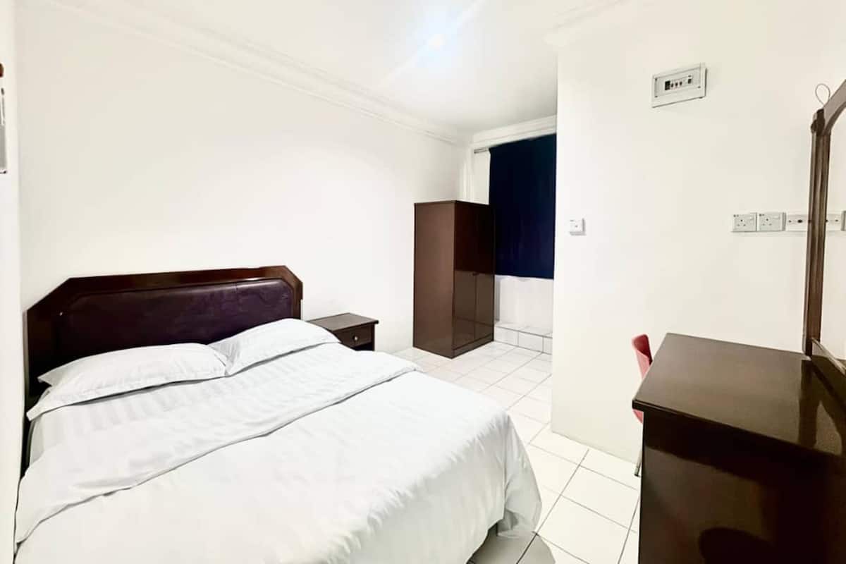 Una habitación de hotel con cama, mesita de noche, armario y escritorio con espejo.