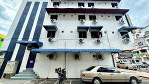 A multi-story hotel with air conditioning units, a blue awning, and a parked car in front. - Hotel O Vaigan Hotel (Bintulu)