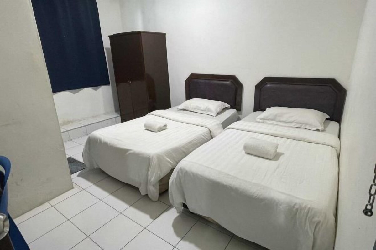 Una habitación con dos camas individuales, un armario y una cortina azul.