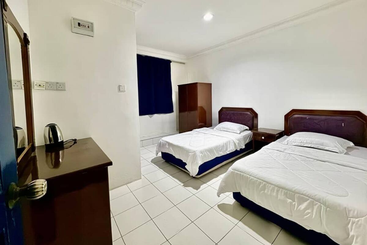 Habitación de hotel con dos camas, un escritorio y un armario.