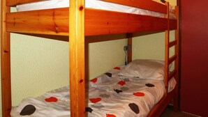 A bunk bed with a wooden frame and a patterned bedspread. - Studio 4 pers. direct access slopes, center and south-facing balcony (Les Orres)