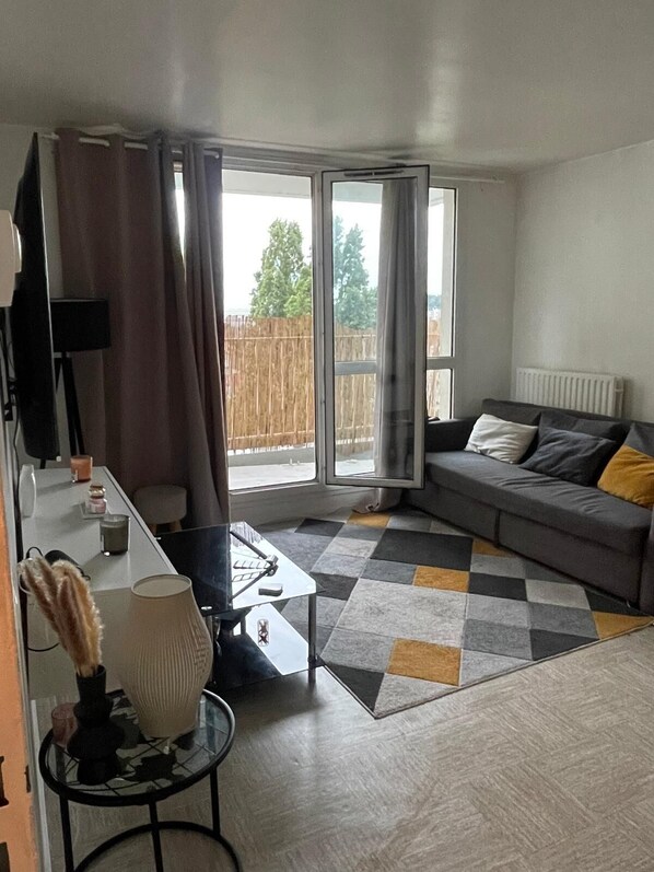 Relax in this stylish living room with a large sofa, coffee table, and side table, set against a backdrop of large windows and a checkered rug.