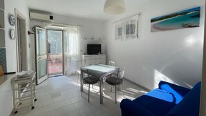 A compact living space with a dining area, a kitchenette, and a balcony with a view. - Duplex la maddalena (Sardegna)