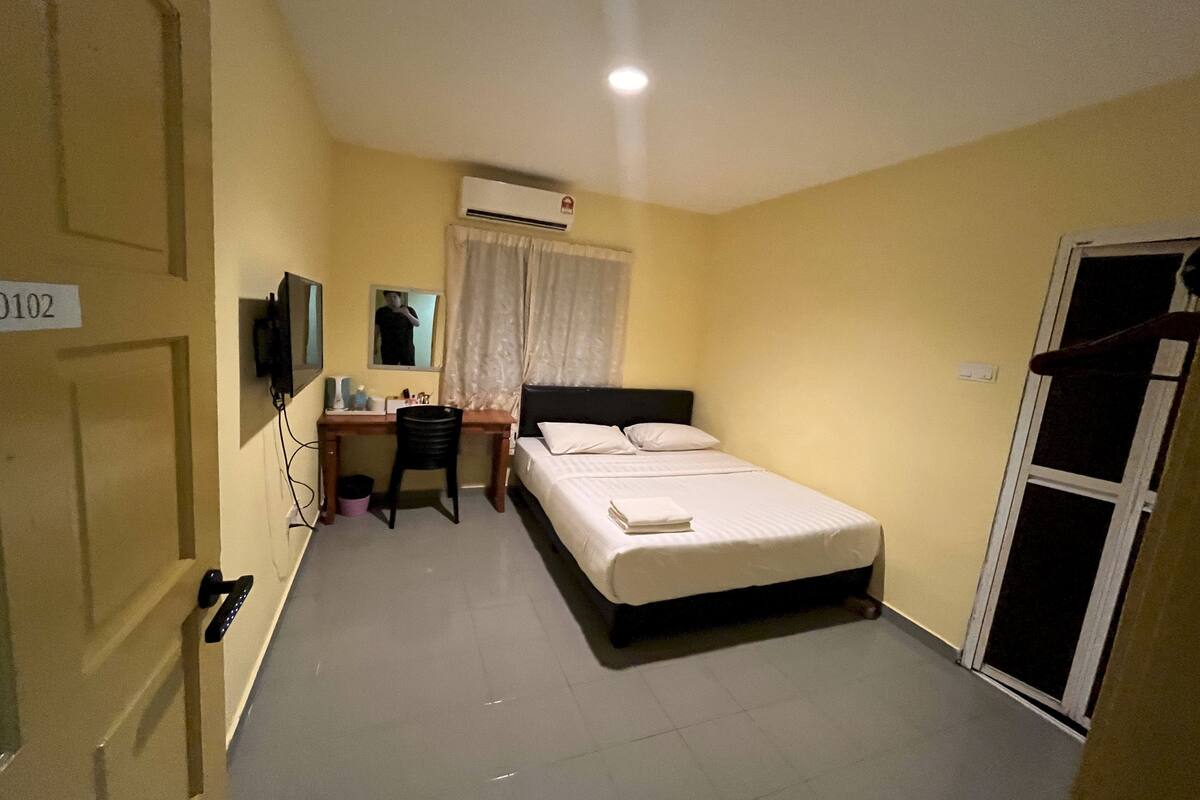 Ein Hotelzimmer mit Bett, Schreibtisch, Stuhl und Klimaanlage.