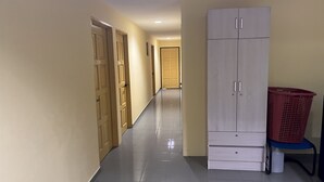 A hallway with a light-colored tiled floor, wooden doors, and a white wardrobe with drawers. - Hotel O RAHMAH SOJOURN CENTRE (Johor Bahru)