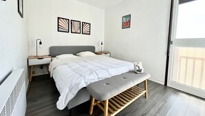 A bedroom with a bed, bedside tables, a bench, and artwork on the walls.