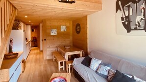 A cozy cabin interior with a wooden ceiling, a dining area, and a sofa.