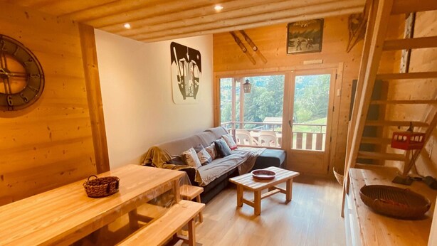 A cozy cabin interior with a wooden bench, a sofa, and a dining table.