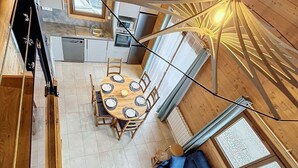 A compact kitchen with modern appliances, a dining area with a round table and chairs, and a cozy seating area with a sofa and a rug. - Comfort chalet 6 pers. with parking and wifi in Le Corbier (Le Corbier)
