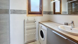 A modern bathroom with a built-in washing machine, a sink, and a mirror. - Comfort chalet 6 pers. with parking and wifi in Le Corbier (Le Corbier)
