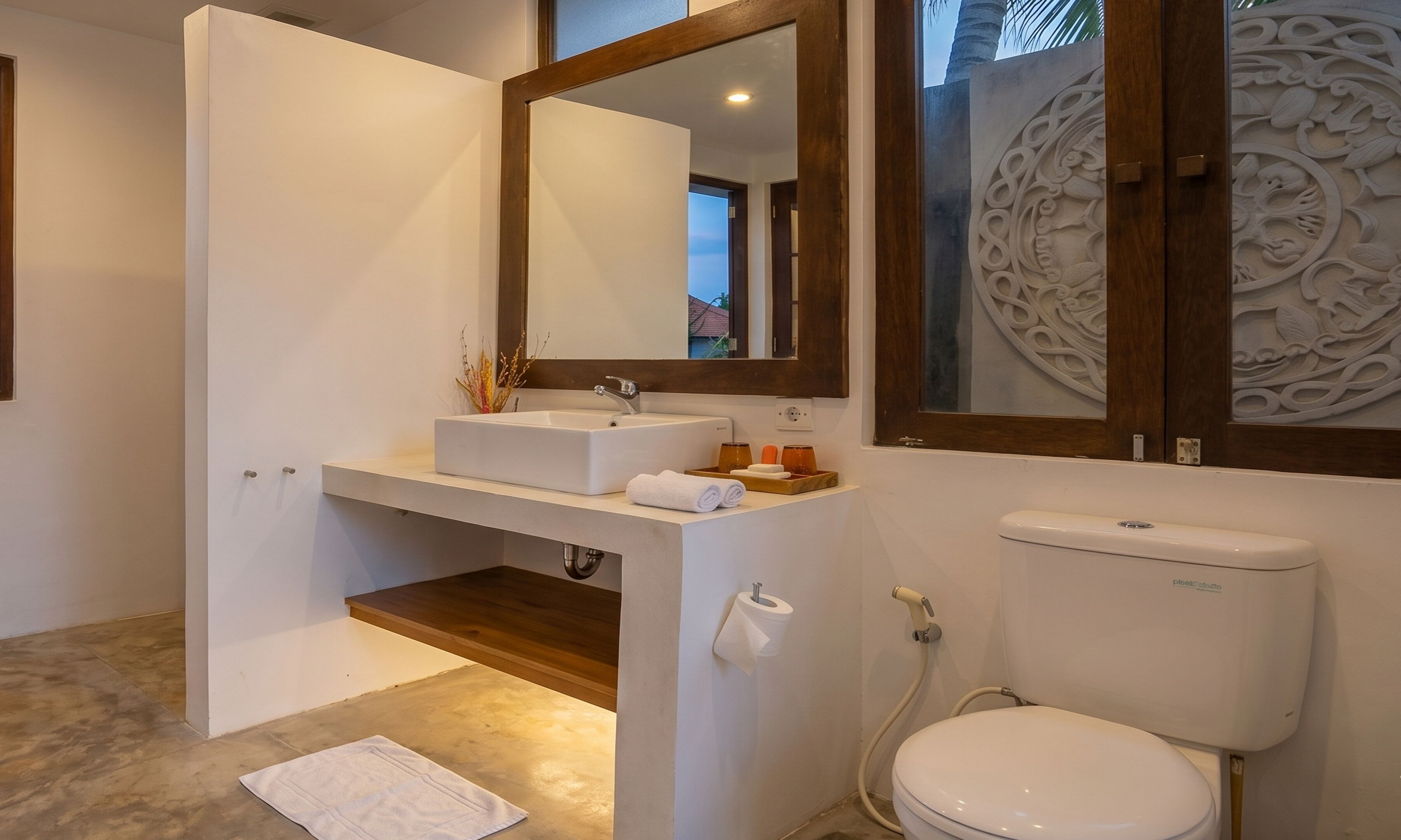 Casa de banho com lavatório branco, espelho e sanita.