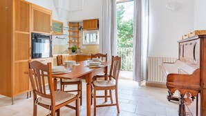Une cuisine spacieuse avec des meubles en bois, une table à manger avec des chaises et un piano.