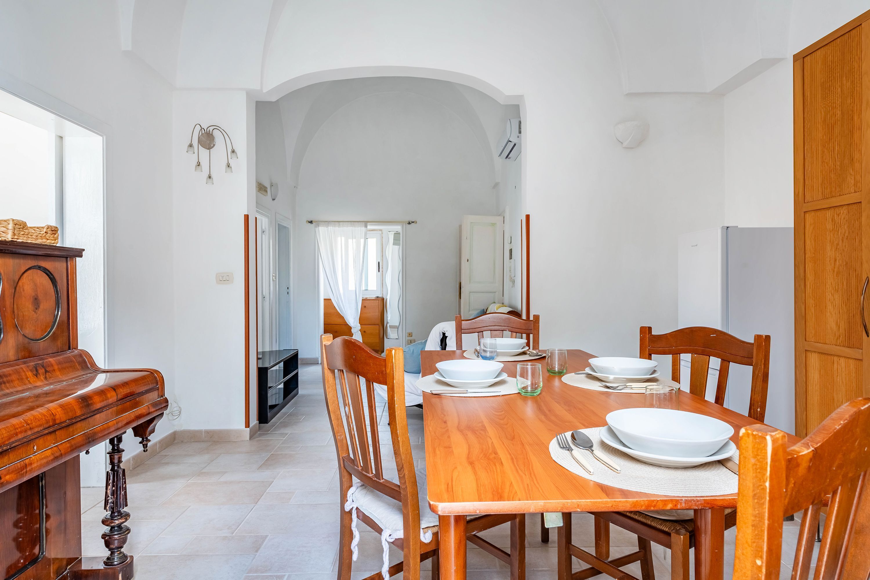 A dining area with a wooden table set for four, surrounded by wooden chairs.
