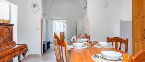 A dining area with a wooden table set for four, surrounded by wooden chairs.