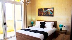A modern hotel room with a large bed, wooden headboard, and a sliding glass door leading to a balcony.