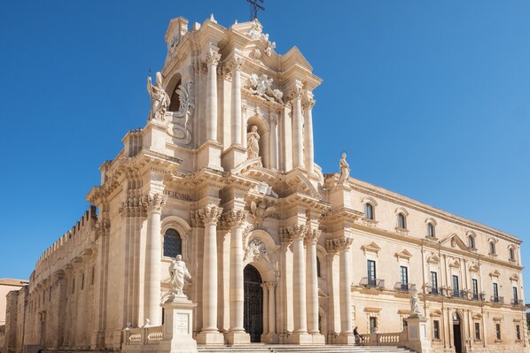 Un edificio grande y ornamentado con arquitectura clásica, que presenta columnas, estatuas y detallados relieves.