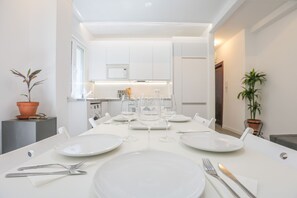 A modern dining area with a white table set for four, including plates, glasses, and cutlery. - Azahar Gran Plaza in Seville (Seville)