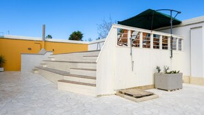 A modern outdoor area with a staircase leading to a covered seating area, a potted plant, and a tiled floor. - Villa Oasi al Mare Near the sea With Pool (Melendugno)