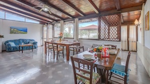 A spacious living area with a wooden ceiling, a dining table set with plates and glasses, and a sofa with cushions. - Villa Oasi al Mare Near the sea With Pool (Melendugno)