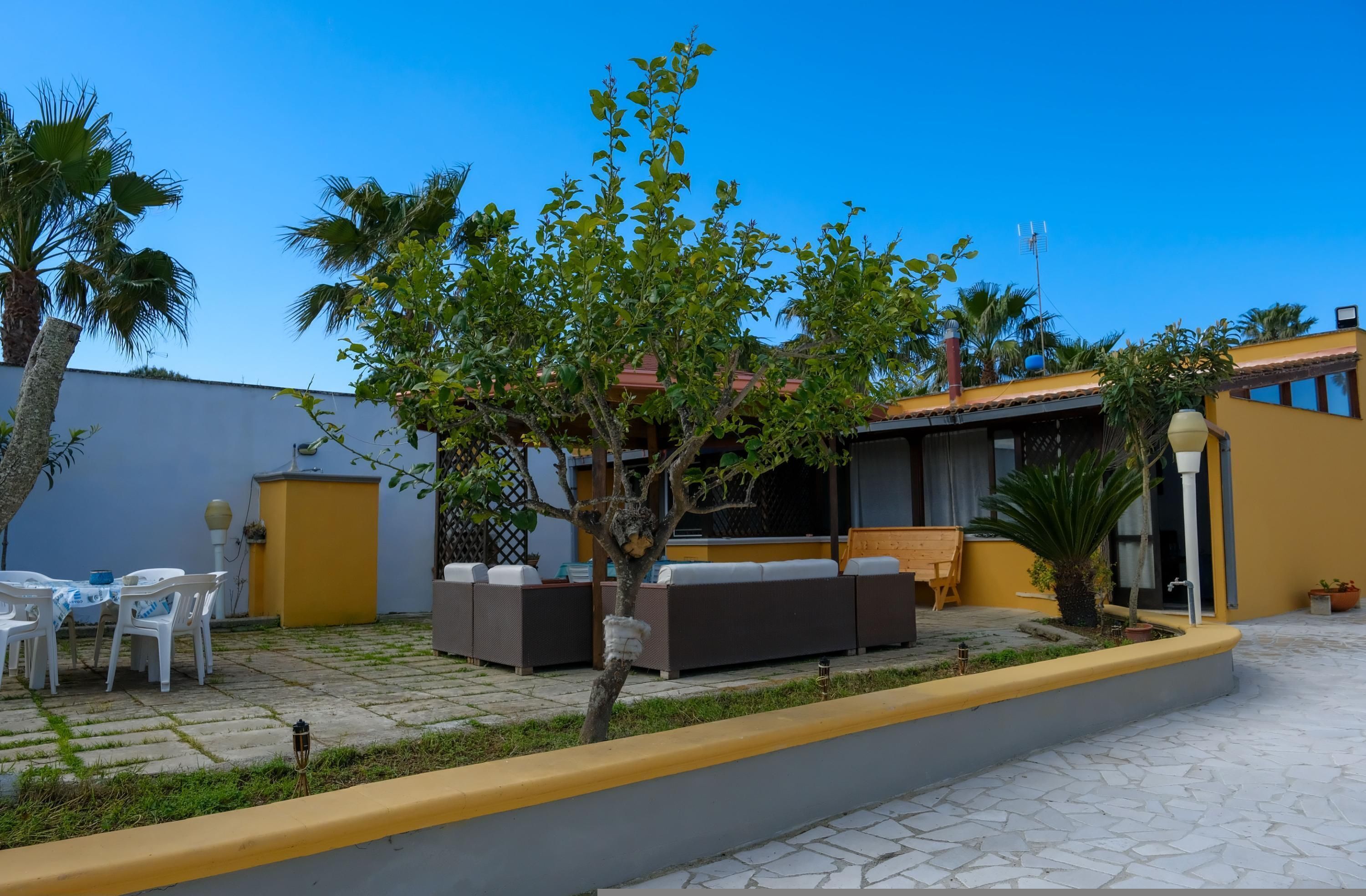 A courtyard with outdoor seating, a small tree, and a building with a yellow facade.