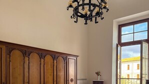 A bedroom with a large bed, a wooden wardrobe, a chandelier, and a view through a window. - Camera famigliare un letto matrimoniale e 1 lettini (Corropoli)